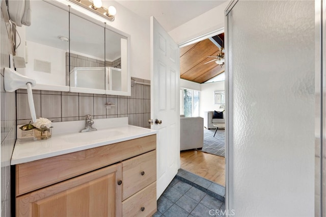 bathroom with ceiling fan, vanity, tile walls, tile patterned floors, and a stall shower