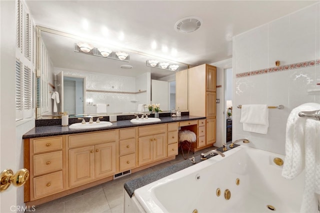 full bath with double vanity, a tub with jets, a sink, and tile patterned floors