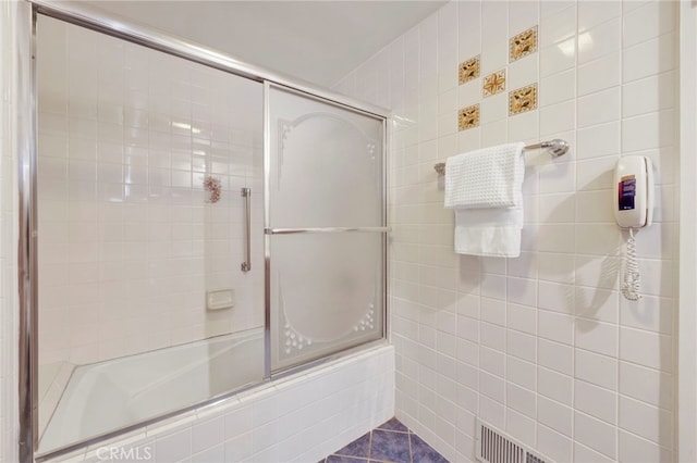 full bath with combined bath / shower with glass door and tile patterned floors