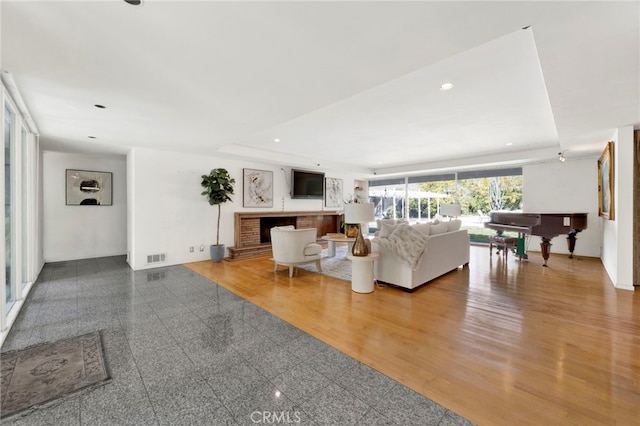 living room featuring granite finish floor, a fireplace, visible vents, and recessed lighting