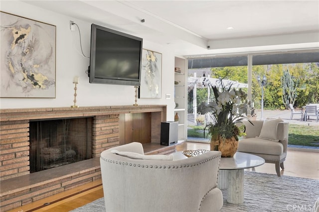 living area with built in shelves, a brick fireplace, and wood finished floors