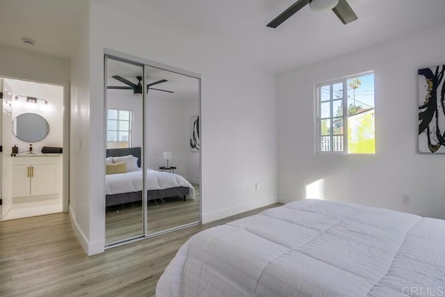 bedroom with a sink, multiple windows, a closet, and light wood-style flooring