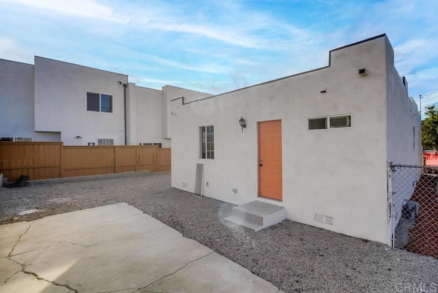 back of house with a fenced backyard and stucco siding