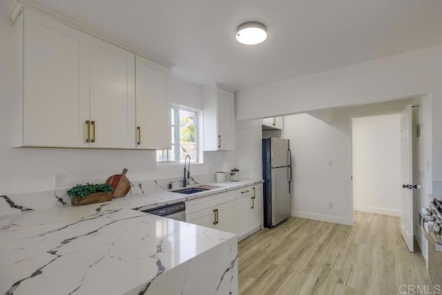 kitchen with light stone counters, stainless steel appliances, light wood-style flooring, white cabinetry, and a sink