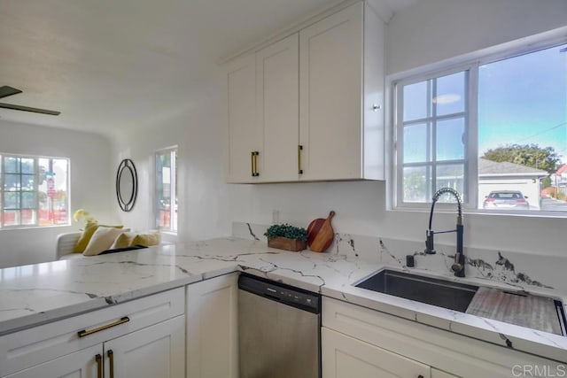 kitchen with light stone counters, a sink, a healthy amount of sunlight, white cabinets, and dishwasher