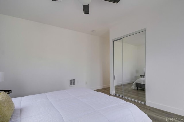 bedroom with dark wood finished floors, a closet, visible vents, ceiling fan, and baseboards