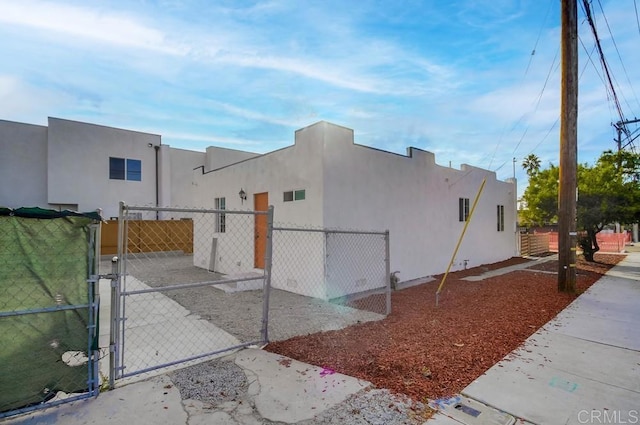 view of home's exterior with fence, a gate, and stucco siding