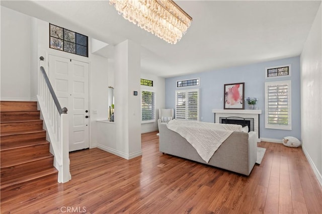 foyer with light wood-type flooring, a fireplace, baseboards, and stairs