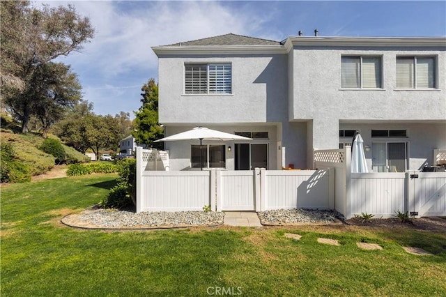 view of front of home with a front yard, fence, and stucco siding