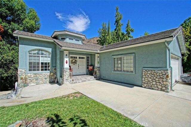 single story home with stone siding, an attached garage, and stucco siding