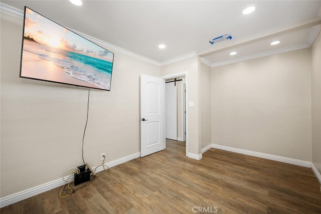 unfurnished bedroom with a barn door, wood finished floors, and baseboards