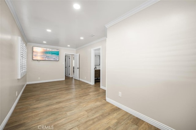 empty room featuring light wood-type flooring, recessed lighting, baseboards, and ornamental molding