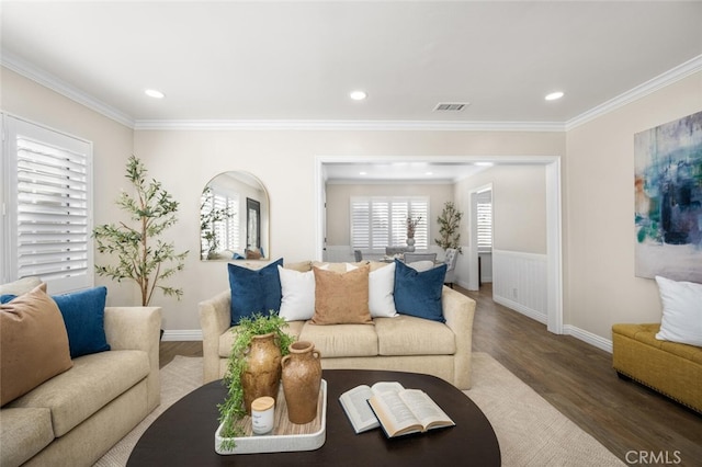 living area with ornamental molding, a wealth of natural light, visible vents, and wood finished floors