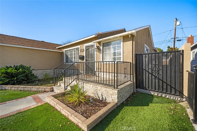 view of front of property featuring a gate, a front lawn, and stucco siding