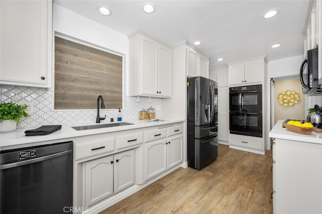 kitchen with black appliances, light wood finished floors, light countertops, and white cabinets