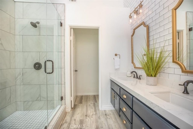 full bath featuring double vanity, wood finished floors, a sink, and a shower stall