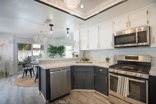 kitchen with a notable chandelier, white cabinetry, appliances with stainless steel finishes, and a sink