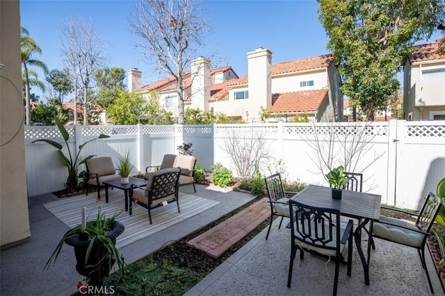 view of patio featuring outdoor dining space, a fenced backyard, and a residential view