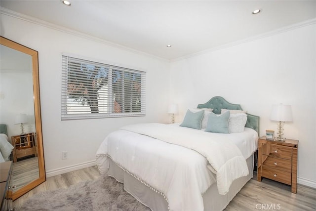 bedroom featuring baseboards, crown molding, and light wood finished floors