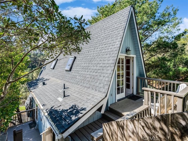 view of side of home with a shingled roof and a wooden deck