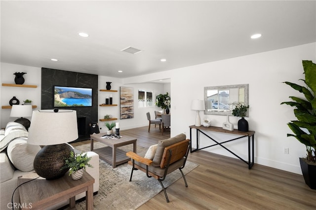 living area with baseboards, wood finished floors, visible vents, and recessed lighting