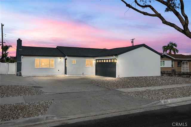 ranch-style home featuring a garage, driveway, fence, and stucco siding