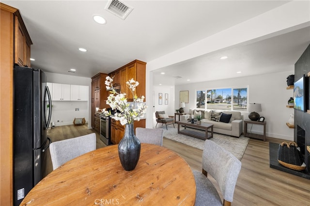 dining area with a fireplace, wood finished floors, visible vents, and recessed lighting