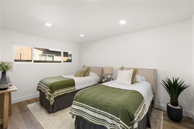 bedroom with baseboards, wood finished floors, and recessed lighting