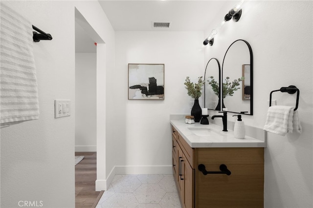 bathroom featuring visible vents, vanity, baseboards, and tile patterned floors