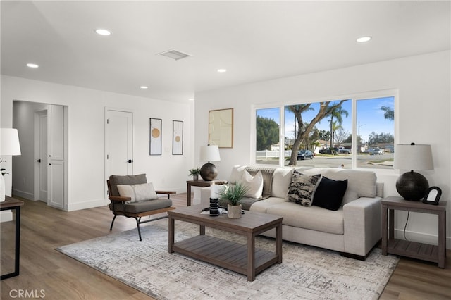 living room featuring light wood finished floors, baseboards, visible vents, and recessed lighting