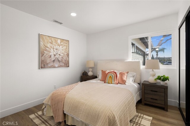 bedroom featuring baseboards, visible vents, wood finished floors, and recessed lighting