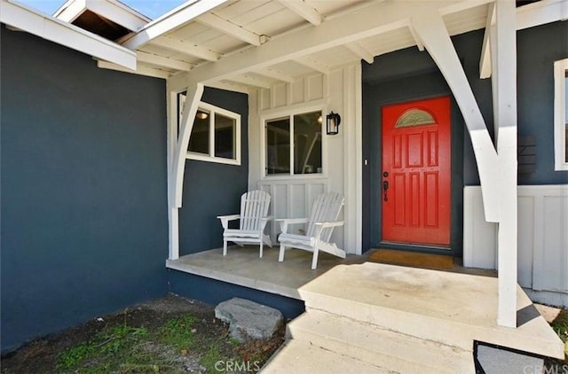 view of exterior entry with covered porch and stucco siding