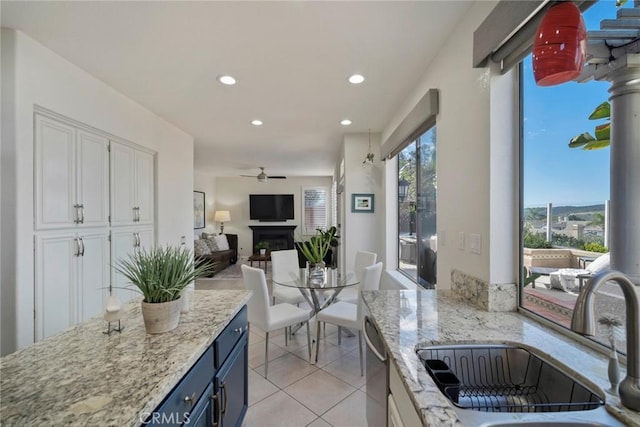 kitchen with white cabinets, dishwasher, blue cabinets, a fireplace, and a sink