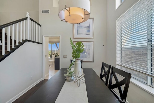 dining room with baseboards, visible vents, stairway, and a towering ceiling