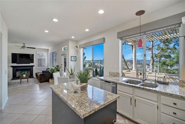 kitchen featuring white cabinets, dishwasher, light stone counters, decorative light fixtures, and a sink