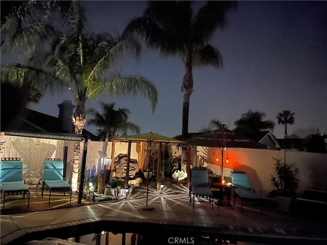 pool at twilight featuring a fenced backyard and a patio