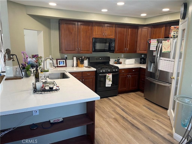 kitchen featuring open shelves, light wood-style flooring, a sink, a peninsula, and black appliances