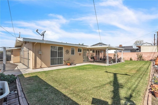 rear view of house featuring a patio area, fence, a lawn, and stucco siding