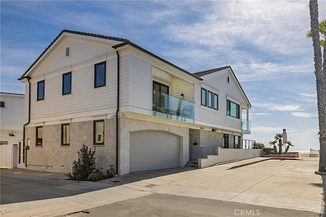 view of front of property featuring stone siding, an attached garage, and driveway