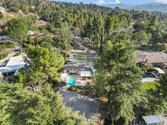 aerial view featuring a wooded view and a mountain view