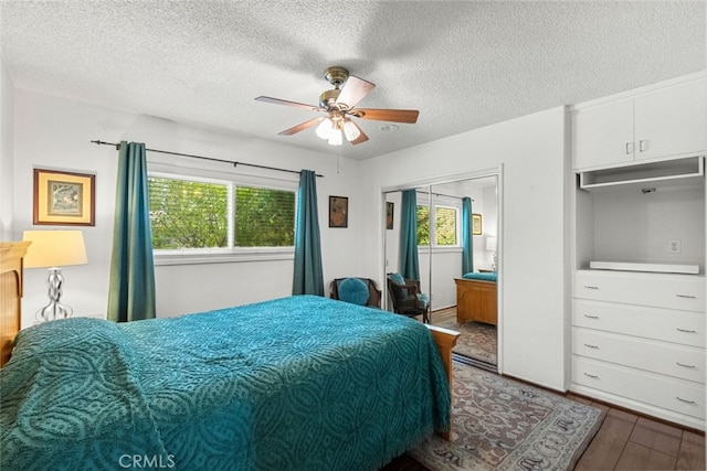 bedroom with a textured ceiling, multiple windows, a ceiling fan, and wood finished floors