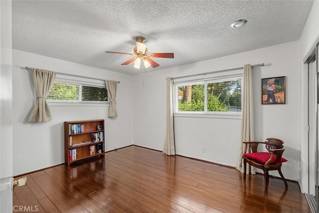 living area featuring ceiling fan, dark wood-type flooring, and a textured ceiling