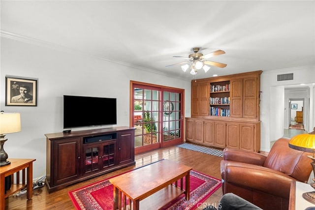 living room featuring light wood-style floors, visible vents, crown molding, and ceiling fan