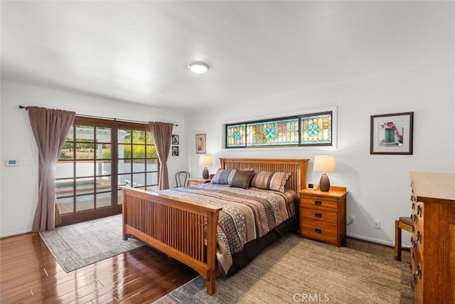 bedroom featuring access to exterior, baseboards, and wood finished floors