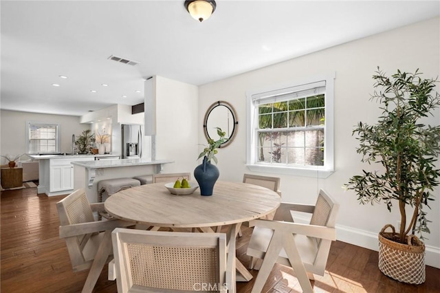 dining room featuring dark wood-type flooring, a healthy amount of sunlight, and visible vents