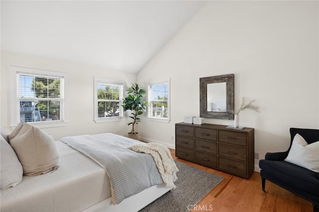 bedroom featuring light wood-type flooring, lofted ceiling, and baseboards