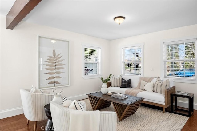 sitting room featuring beam ceiling, plenty of natural light, baseboards, and wood finished floors