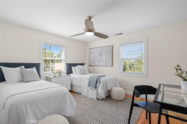 bedroom with light wood-style flooring, visible vents, ceiling fan, and baseboards