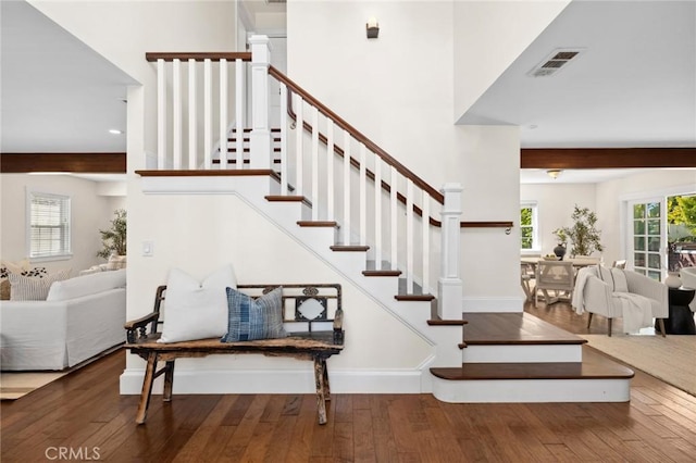 staircase with beamed ceiling, wood finished floors, and visible vents