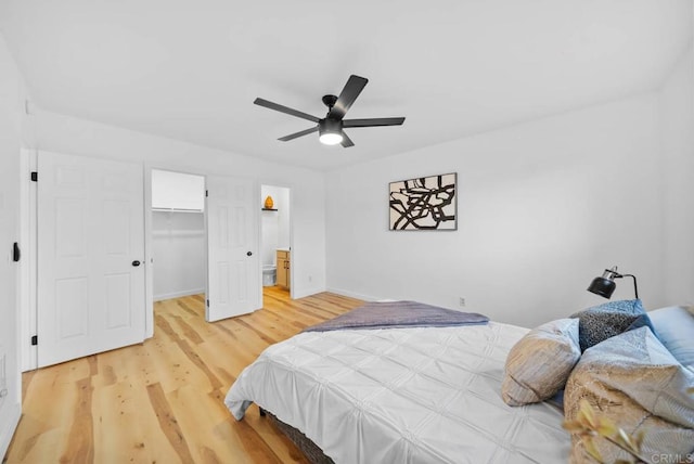 bedroom with ceiling fan, wood finished floors, baseboards, a closet, and a walk in closet